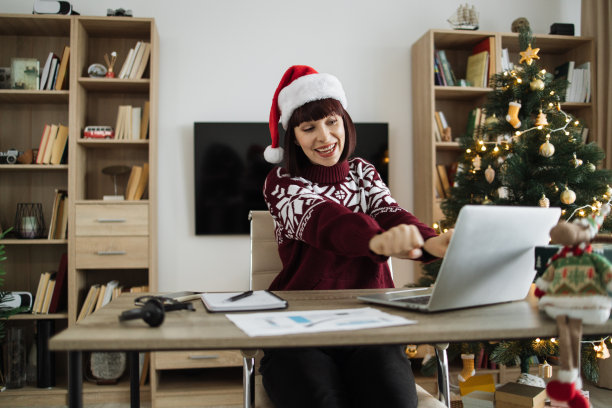 成功的女人戴着圣诞老人的帽子，穿着温暖的冬衣，兴奋地跳舞图片下载