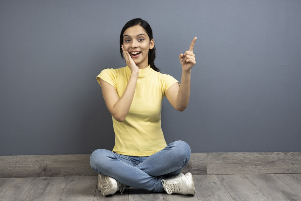 漂亮的女孩指着空的空间显示黑色星期五的价格穿着木地板上的休闲服，库存照片图片下载