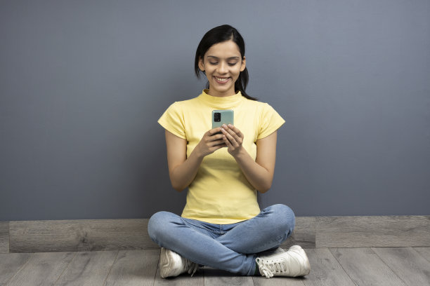 年轻女子在木地板上使用手机的照片图片下载