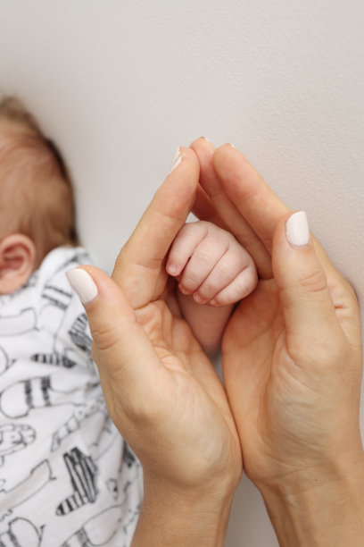 父母的手握着新生婴儿的手指。一对父母的手握着一个新生婴儿的拳头(特写)。家庭保健和医疗保健。白色背景的专业照片图片下载