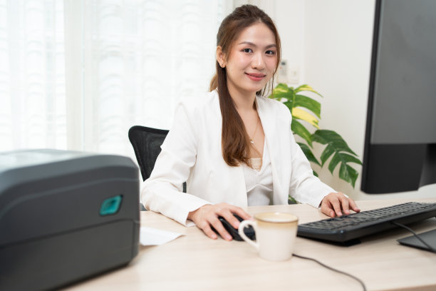 亚洲妇女使用个人电脑打印数据，并在标签贴纸上打印二维码。图片下载