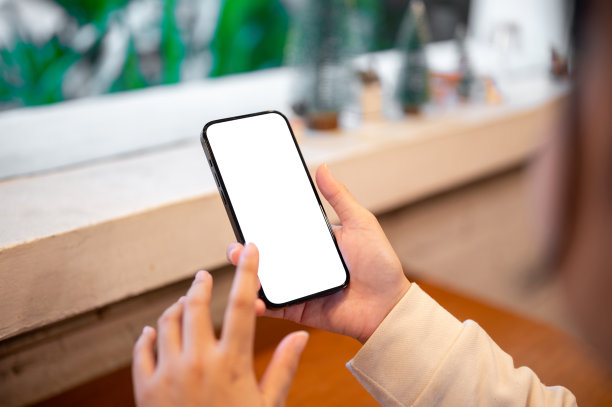 一位女士坐在咖啡店靠窗边玩手机的特写照片。图片下载