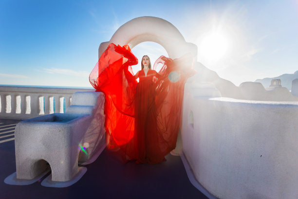 魅力的照片。女孩在大海的背景下挥舞着一件飘逸的红色连衣裙图片下载