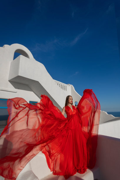 魅力的照片。女孩在大海的背景下挥舞着一件飘逸的红色连衣裙图片下载