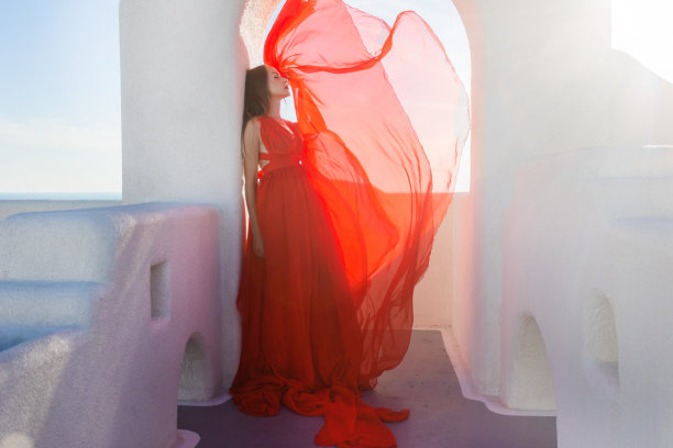 魅力的照片。女孩在大海的背景下挥舞着一件飘逸的红色连衣裙图片下载