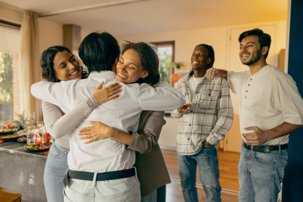 一群微笑的朋友在家庭聚会上开心地见面和拥抱。高质量照片图片下载