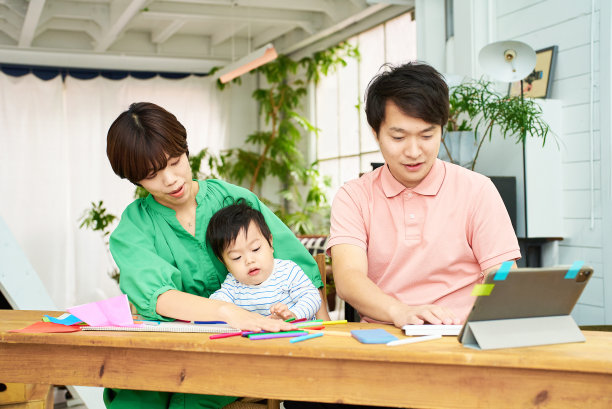 一个抱着孩子的女人和一个在房间里操作电脑的男人图片下载