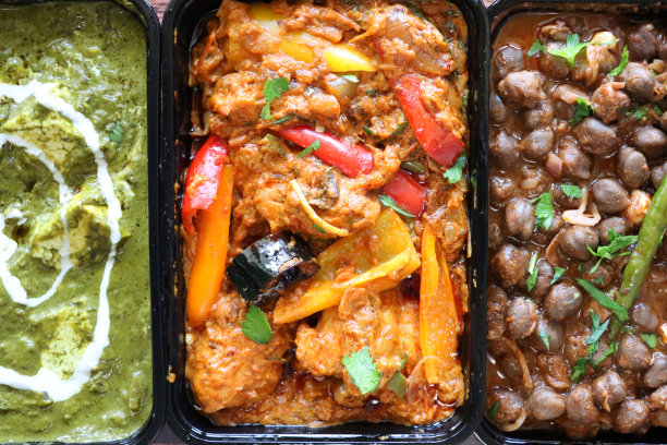 全画幅图片精选印度外卖菜黑色塑料，一次性食品容器，食谱包括，卡代鸡，Palak奶酪(白干酪和菠菜泥)，Pindi辣椒酱(鹰嘴豆咖喱)，高架视图图片下载