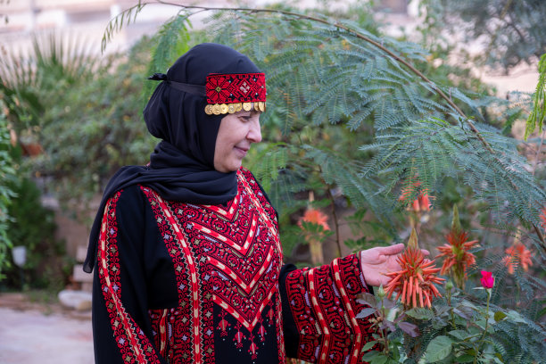 一名妇女穿着巴勒斯坦服装，周围有鲜花和玫瑰图片下载