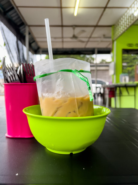 一张特写照片，桌子上粉色的容器里装着勺子和叉子，绿色的容器里装着一包雀巢咖啡。图片下载