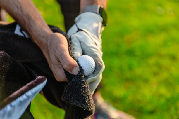 特写的男性高尔夫球手的手，因为他刷/清洁高尔夫球场上的高尔夫球-股票照片图片下载