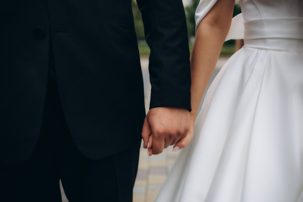 一男一女戴着结婚戒指的照片。年轻的新婚夫妇手牵着手，举行婚礼。新婚夫妇戴着结婚戒指的手。图片下载