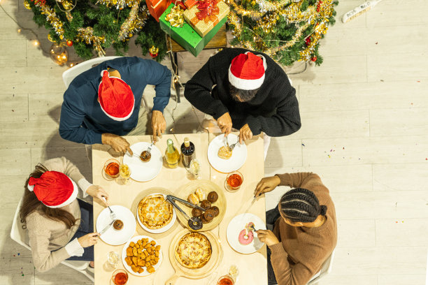 亚洲朋友男女庆祝的俯视图。一个女人在桌子上端着披萨，还有零食和饮料。快乐朋友平安夜庆祝宴会美食和香槟酒。图片下载