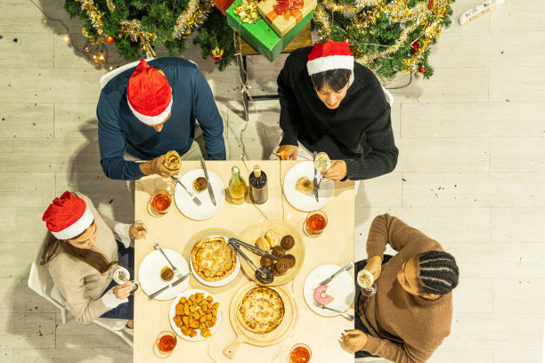 亚洲朋友男女庆祝的俯视图。一个女人在桌子上端着披萨，还有零食和饮料。快乐朋友平安夜庆祝宴会美食和香槟酒。图片下载