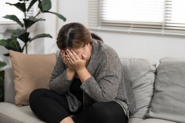 悲伤超重的女人在沙发上思考问题，沮丧的女孩因为糟糕的关系而感到孤独和悲伤，抑郁的女人精神健康失调。图片下载