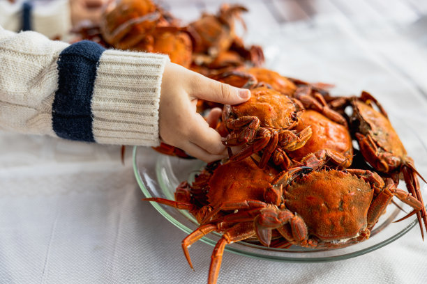 一个小女孩手里拿着一盘螃蟹的特写图片下载