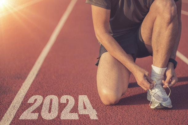 年轻的跑步者在标有2024的跑道上系鞋带图片下载