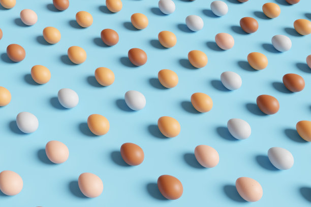 不同颜色的鸡蛋整齐地放在蓝色的背景上。说明乳制品的概念图片下载