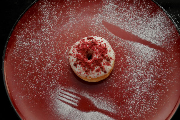 在红盘子上放着糖的甜甜圈图片下载