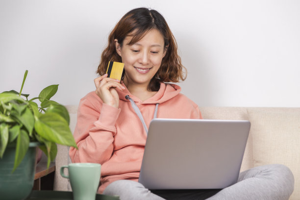 在线购物：一位穿着休闲服的女人在沙发上玩电脑图片下载