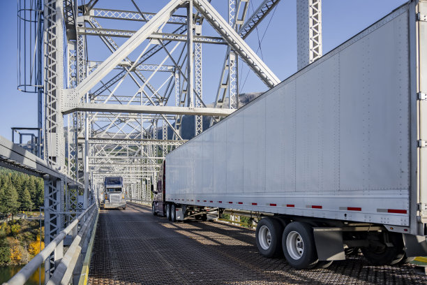 两辆装载着半挂车的大型工业钻机半卡车在一座狭窄的桁架桥上相遇，很难避开对方图片下载