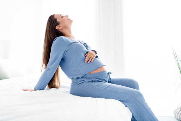 侧面照片可爱可爱开朗的妈妈坐在舒适的沙发上享受周末假期在家里的灯光室图片下载