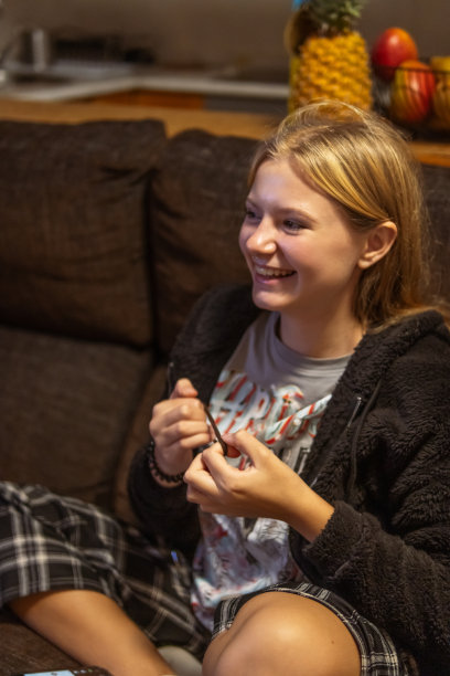 外表轻盈的快乐少女坐在房间里一张深色的沙发上，竖着照片。快乐的童年图片下载