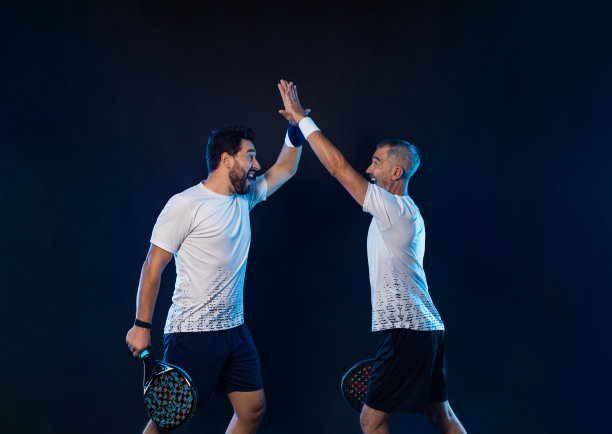 乒乓球双打。两个运动员拿着球拍。男子运动员与球拍在球场上的霓虹灯颜色。体育的概念。下载一张高质量的照片，用于设计一个体育应用程序图片下载