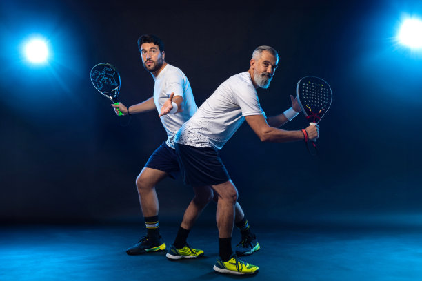 乒乓球双打。两个运动员拿着球拍。男子运动员与球拍在球场上的霓虹灯颜色。体育的概念。下载一张高质量的照片，用于设计一个体育应用程序图片下载