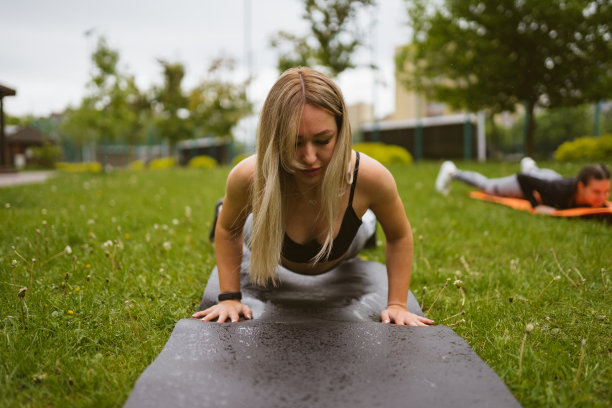 金发女郎躺在运动组附近的垫子上做俯卧撑图片下载