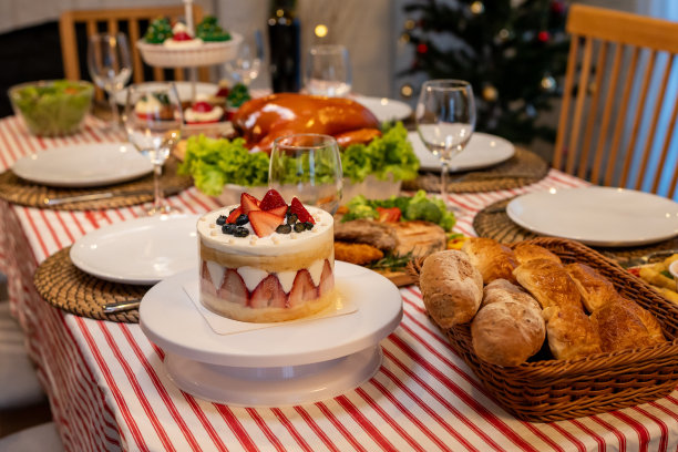 圣诞火鸡和许多食物在装饰房间的桌子上的照片。烤火鸡、青菜沙拉和甜点盛在盘子里，供家庭聚餐时享用。图片下载