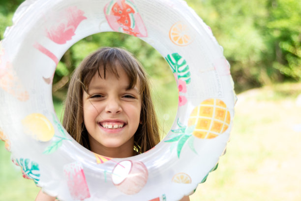 一个可爱的小女孩拿着游泳圈站在河岸上看着镜头图片下载