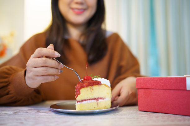 快乐的亚洲妇女吃美味的圣诞fruitÂ蛋糕。圣诞晚餐派对配上美味的圣诞蛋糕，有新年和圣诞的概念图片下载