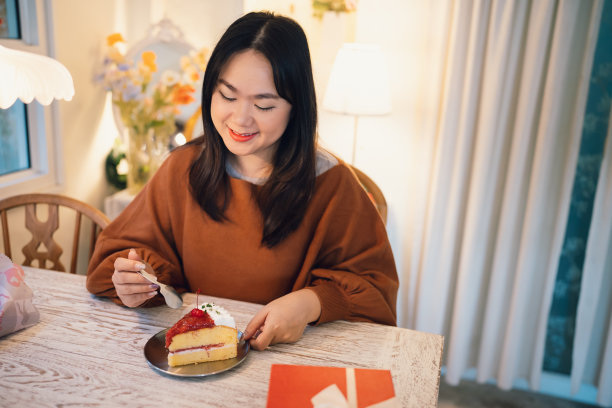 快乐的亚洲妇女吃美味的圣诞fruitÂ蛋糕。圣诞晚餐派对配上美味的圣诞蛋糕，有新年和圣诞的概念图片下载