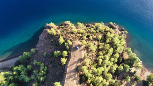 这张航拍照片显示，一辆孤零零的汽车停在海边一片绿树成荫的偏远地区。图片下载