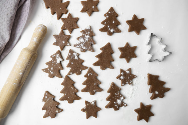 制作圣诞饼干的过程。这张照片以白色为背景，展示了新年饼干的面团、擀面杖和模具。从上面看。图片下载