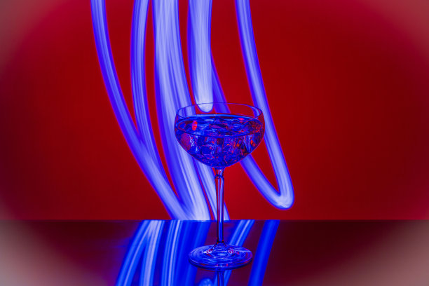 近距离观察酒精饮料与冰块在红色背景的水晶玻璃。图片下载