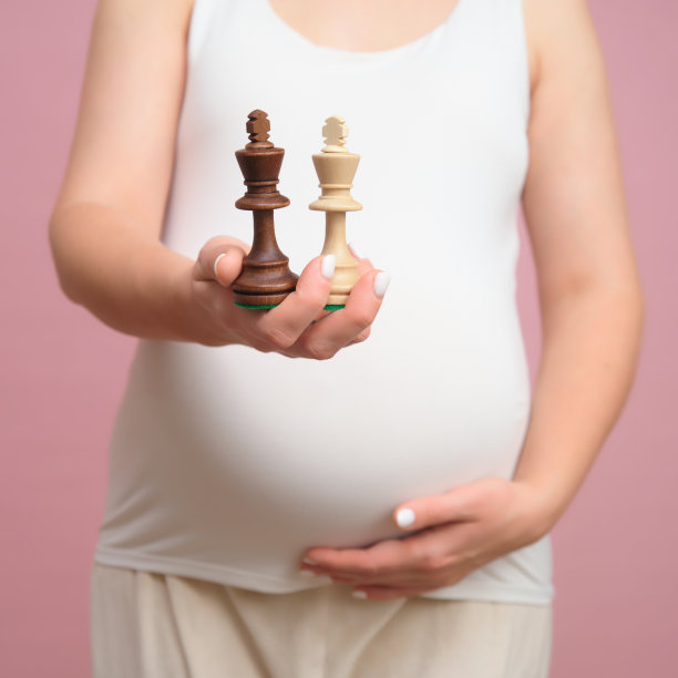 孕妇手里拿着棋王，工作室粉色背景图片下载
