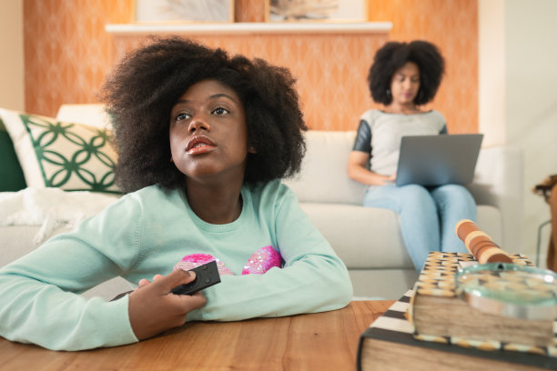 十几岁的女儿在看电视，妈妈在客厅工作图片下载