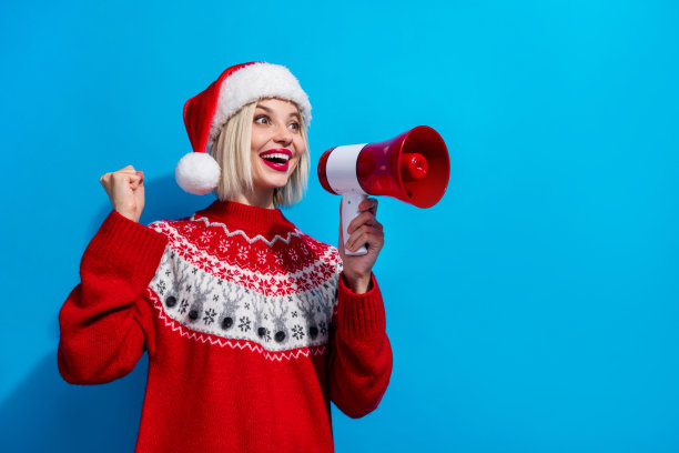 照片上的幸运女子被圣诞老人精灵女士穿着装饰套头衫的叫声打动了，背景是一片空旷孤立的蓝色图片下载