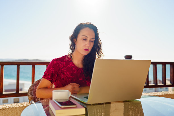 西班牙裔妇女在公寓阳台上用笔记本电脑工作图片下载