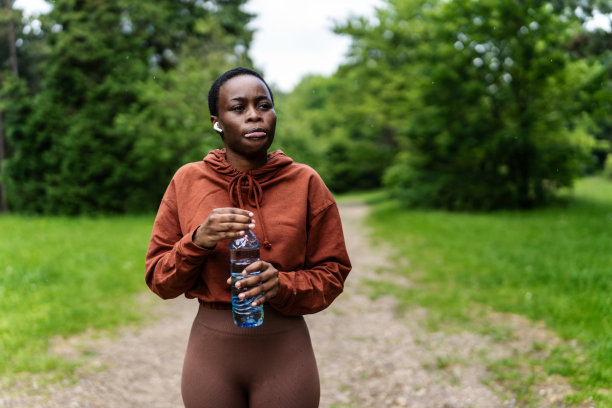 一名年轻女子在锻炼中休息喝水的照片。图片下载