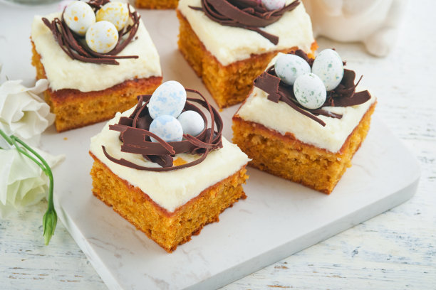 复活节胡萝卜蛋糕棒装饰巧克力窝和巧克力糖蛋开花樱桃或苹果花在乡村轻木制背景。复活节的节日大餐。传统的复活节食物。图片下载