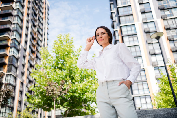 照片中华丽自信的女士穿着时尚的衣服，戴着眼镜走在城市温暖的春光明媚的户外图片下载