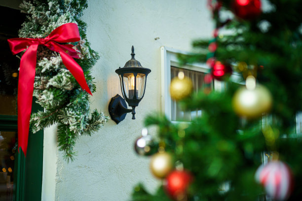 圣诞快乐，墙上挂着复古的铁灯笼，彩球，还有圣诞祝福图片包裹，绿色圣诞树背景上的铃铛装饰。图片下载