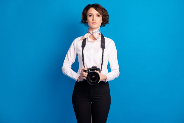照片的华丽集中的年轻女孩手臂持有相机绑在脖子围巾孤立的蓝色背景图片下载