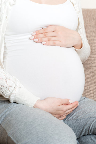 可爱的白人未来妈妈的照片躺在明亮的客厅沙发上，手放在肚子上图片下载