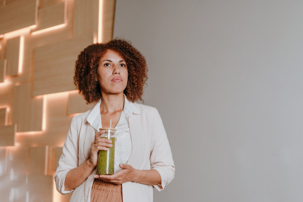 在办公室用竹竿喝绿色奶昔的女人图片下载