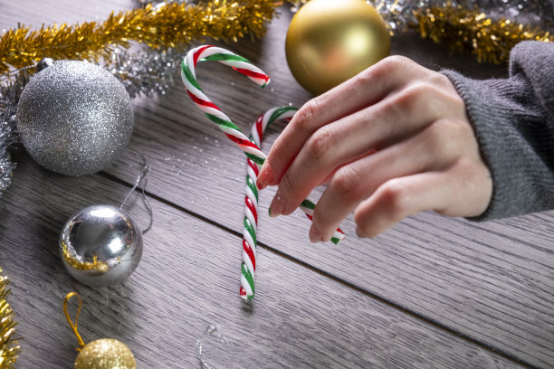 一位年轻女子用玩具装饰圣诞树。她有一幅关于圣诞节的指甲画。准备假期的股票照片图片下载