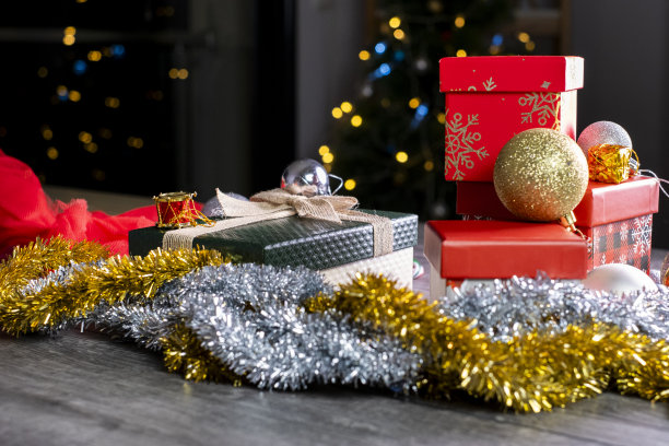 圣诞树前的桌子上放着圣诞装饰的礼品盒图片下载